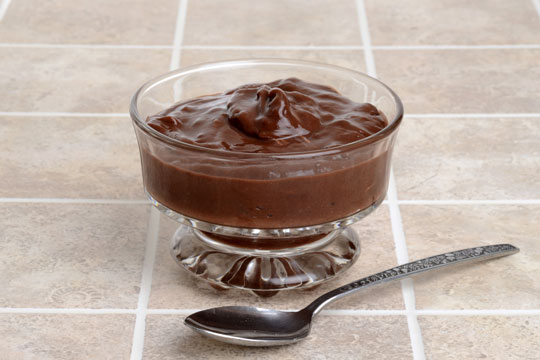 chocolate pudding and spoon on a tile countertop