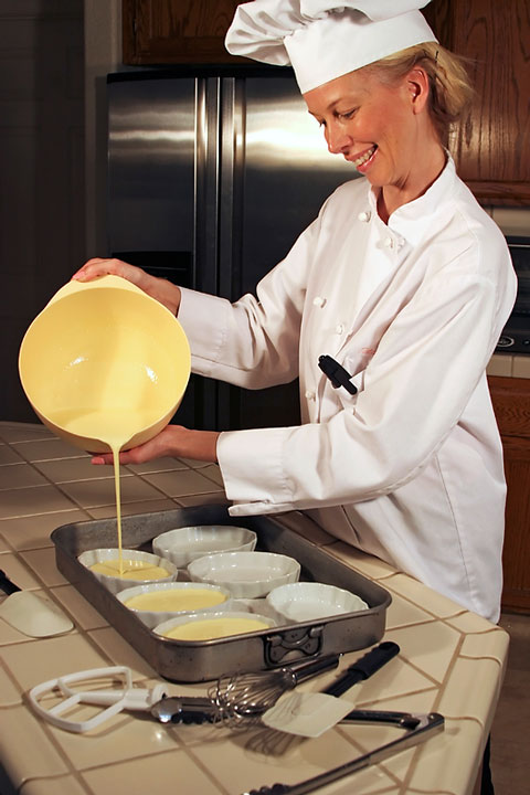 baker using a tile countertop surface to pour dough into ceramic tart pans